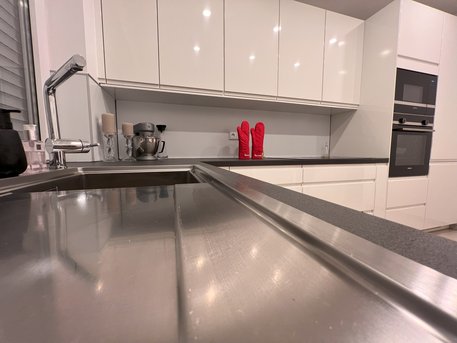 Referenzküche in Weiß Lack Hochglanz mit Arbeitsplatte in Schwarz geflammt von Ihrem Küchenstudio in Aachen